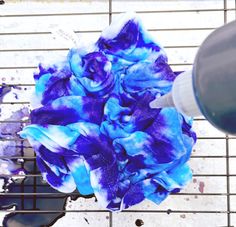 a blue and white flower sitting on top of a metal grate next to a bottle