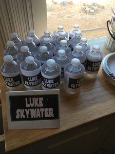 there are many bottled water bottles on the counter next to a plate with a sign that says luke skywater