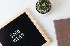 a wooden sign that says good vibes next to a potted cactus