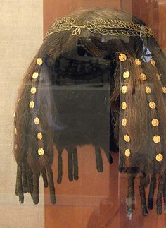 an elaborate headdress is on display in a glass case with gold buttons and chains