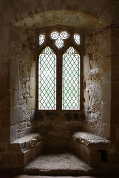 a stone bench in front of a stained glass window