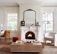 a living room filled with furniture and a fire place in front of a mirror on the wall