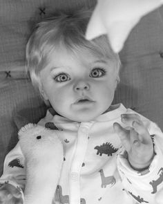 a black and white photo of a baby holding a stuffed animal