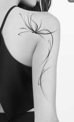 the back of a woman's shoulder with an artistic tattoo design on her arm