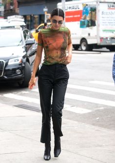 a woman is walking down the street in high heels