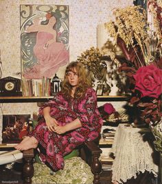 a woman sitting on top of a chair next to flowers