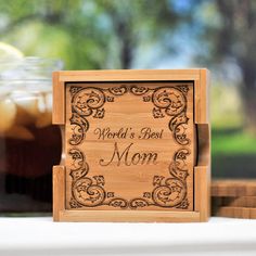 a wooden box with the words world's best mom on it sitting next to some drinks