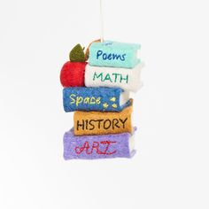 an ornament hanging from a string with books and apples on it that says, proms math space history art