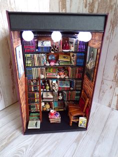 an open book case filled with books on top of a white wooden floor next to two lamps