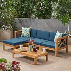 a blue couch sitting on top of a wooden table next to a planter filled with flowers