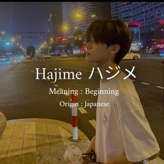 a young man standing on the side of a road next to a traffic light at night