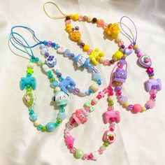 several colorful bracelets are laying on a white sheet and have hello kitty charms attached to them