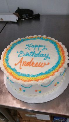 a birthday cake with the words happy birthday and rainbows on it sitting on a table