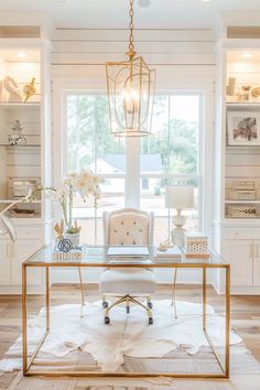 a white and gold desk in the middle of a living room with lots of windows