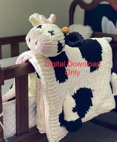 a crocheted cow blanket sitting on top of a wooden bed frame next to a baby crib