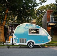 a blue and white trailer parked on the side of a road next to a tree