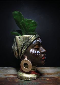 an african woman's head is adorned with green leaves