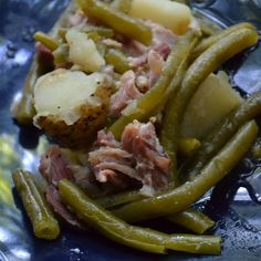 a blue plate topped with green beans and potatoes