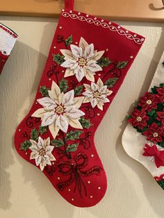 three christmas stockings hanging on the wall with poinsettis and holly decorations attached to them