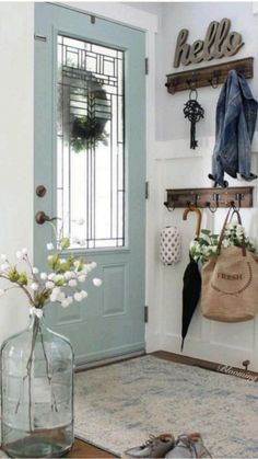 a vase with flowers sitting on the floor next to a blue door and some hooks