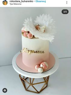 a pink and white cake with angel wings on top is displayed in the instagramture