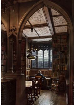 an arched doorway leads into a library with bookshelves and tables in the center