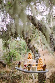 a cake sitting on top of a metal tray under a tree filled with lots of food