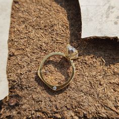 a diamond ring sitting on the ground next to a piece of wood shavings