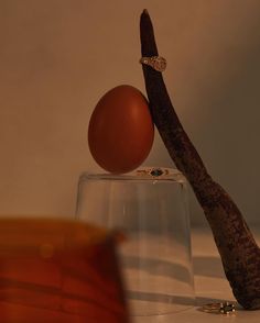 an egg is sitting on top of a glass with a wooden stick sticking out of it