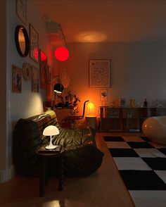 a living room with black and white checkered flooring, green leather couch, red lamps and pictures on the wall