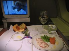 an airplane tray with food and wine in front of a television set on the plane