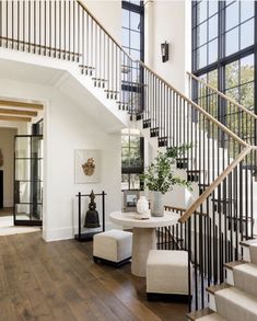 a white staircase with black railing and wooden flooring next to a glass doored entryway