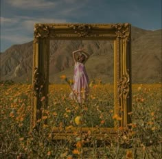 a woman is standing in a field with yellow flowers and a gold frame on the ground