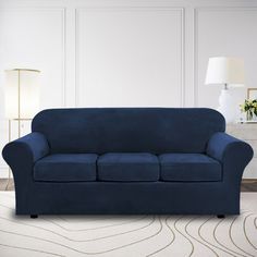 a living room with a blue couch and white rugs on the floor next to a lamp