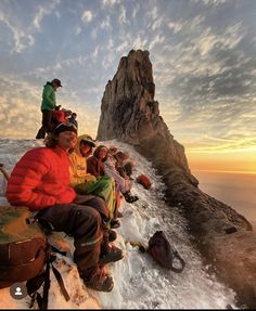 a group of people sitting next to each other on top of a snow covered mountain