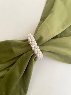 a close up of a tie with pearls on it's end and green fabric