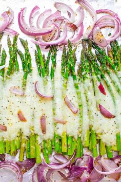 asparagus and onions are being prepared on a sheet of parchment with white sauce