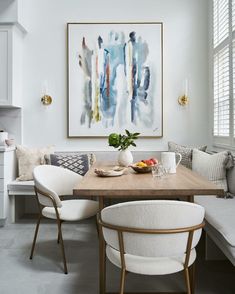 a dining room table with two chairs and a painting on the wall above it,