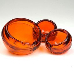 three orange glass bowls sitting next to each other