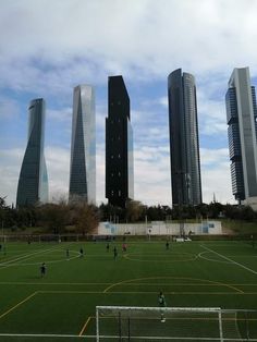 several people playing soccer on a field in front of tall buildings