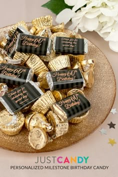 a plate full of gold foiled chocolates on a table next to white flowers