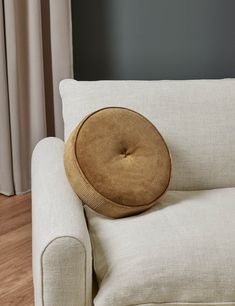 a white couch with a round pillow on it's back and armrests