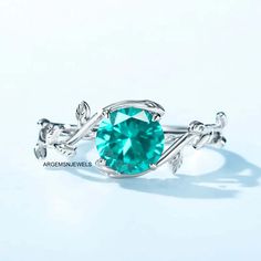 a ring with a green stone in the center and leaves on it's side