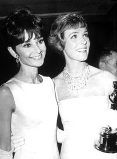 two women standing next to each other holding an oscar award in front of their faces