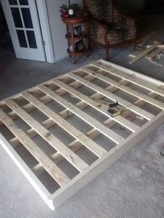 a bed frame made out of wooden planks in the middle of a living room