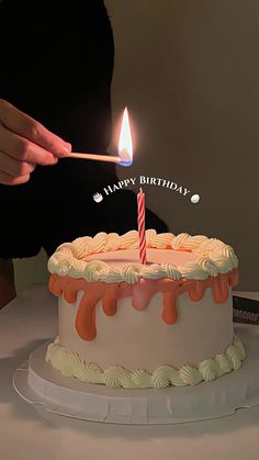 a person lighting a candle on a birthday cake