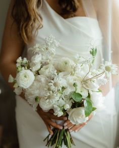 a bride holding a bouquet of white flowers