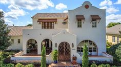 a large white house with lots of windows and plants around it's front entrance