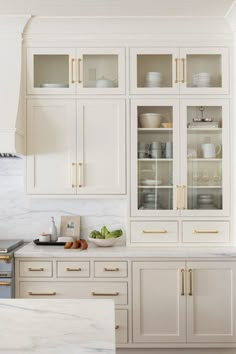 a kitchen with white cabinets and marble counter tops