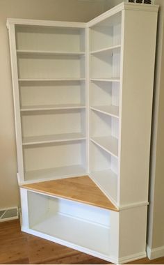 an empty white bookcase in the corner of a room